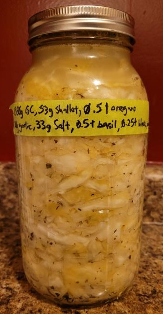 A side picture of the ferment. The cabbage is becoming a greyish yellow 
      and translucent, there are many air pockets, and the liquid has become entirely opaque.